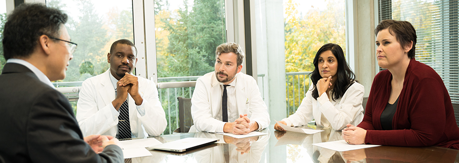A group of doctors and providers sitting at a conference table.