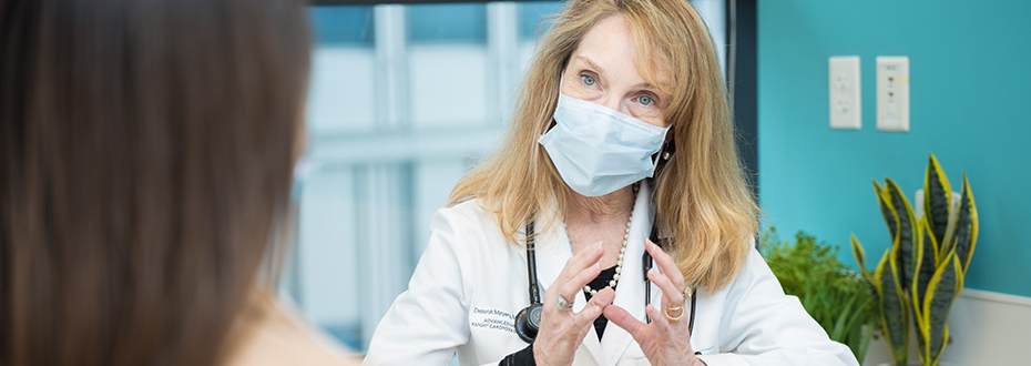 Dr. Deborah Meyers, wearing a PPE facemask, providing an explanation to a female patient.