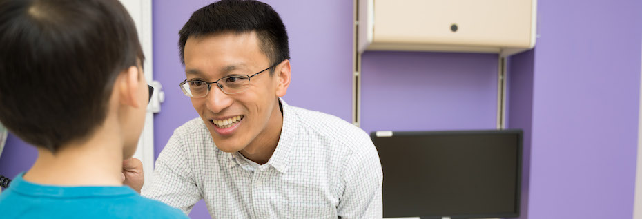 Photo of a healthcare provider with a child in an exam room with a purple wall