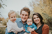 A family portrait of a wife and her husband holding their baby and toddler.