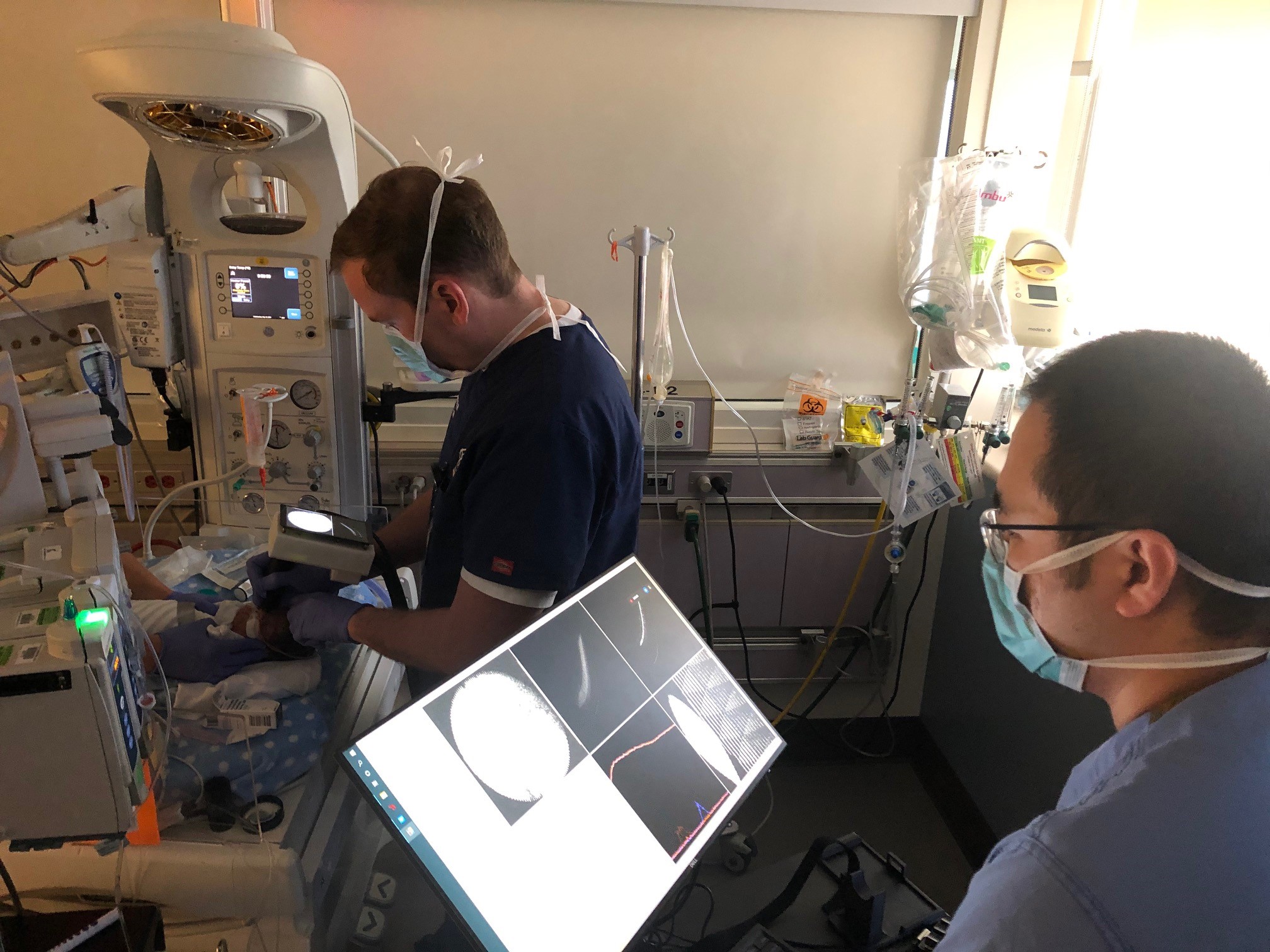 Drs. Campbell and Jian take images of an infant's retina using a new OCTA device.