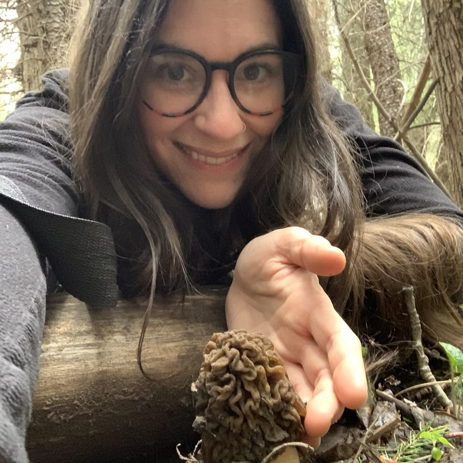 Doctor Brooke Bachelor posed outdoors, with a mushroom