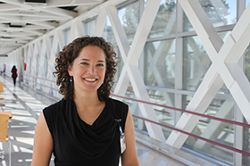 A woman smiling as she stands in the 博彩网站 skybridge to the Portland VA Hospital.