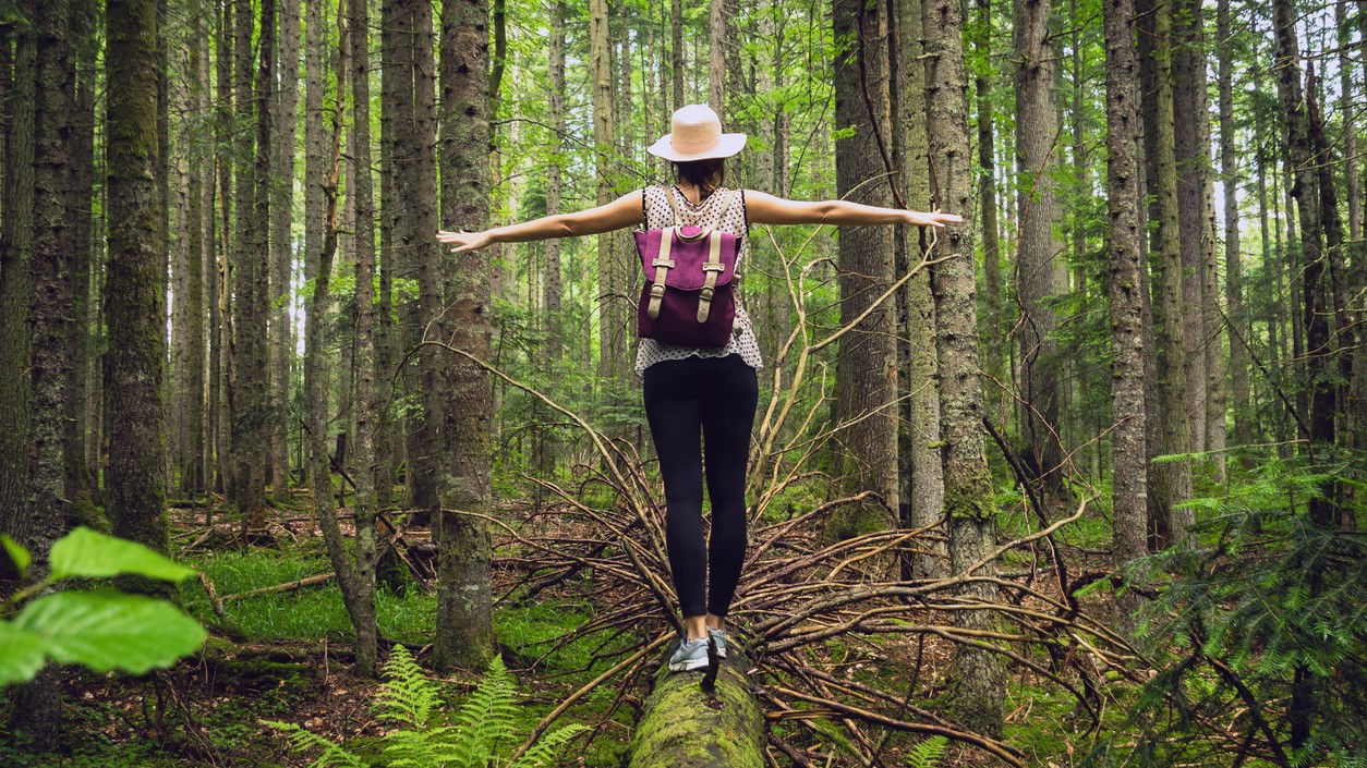 Woman balances on a log in the forest