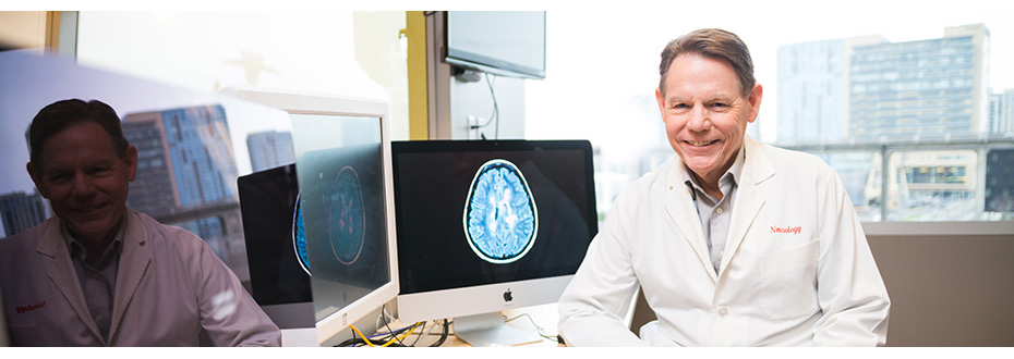 Dr. Dennis Bourdette, M.D., FANA, FAAN, in a lab coat in front of a computer at the 博彩网站 Multiple Sclerosis Center