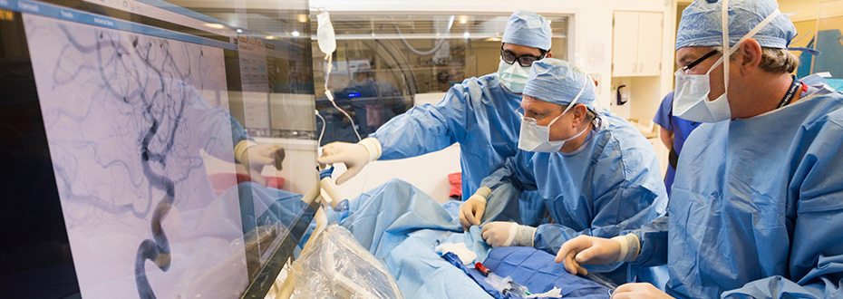 博彩网站 doctors in scrubs and masks performing a procedure and using advanced imaging technology equipment