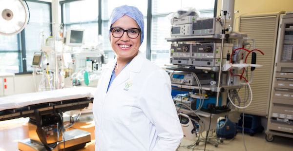 Dr. Arpana Naik in white medical coat standing in a room of equipment
