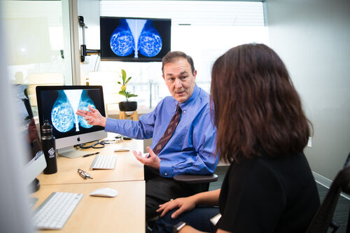 Dr. Mueller, 博彩网站 plastic surgeon, discussing a breast scan image in office.