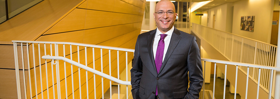 A portrait photo Dr. Ahmed Raslan, a neurosurgeon at 博彩网站 in a grey suit and purple tie