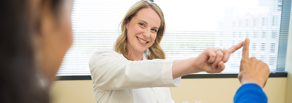 Shannon Anderson, a physician assistant at the 博彩网站 Parkinson Center touching fingers with a patient