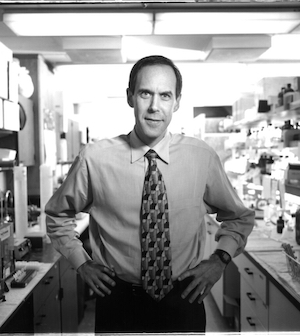 Black-and-white photo of Dr. Brian Druker standing in a research lab