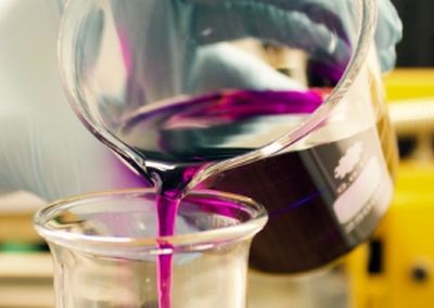 Beaker full of pink liquid pouring in to a large test tube.