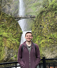 A man smiling in front of Multnomah Falls.