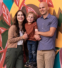 A child smiling in between his parents, also smiling.