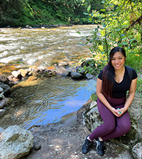 A woman sitting on a rock next to a river.
