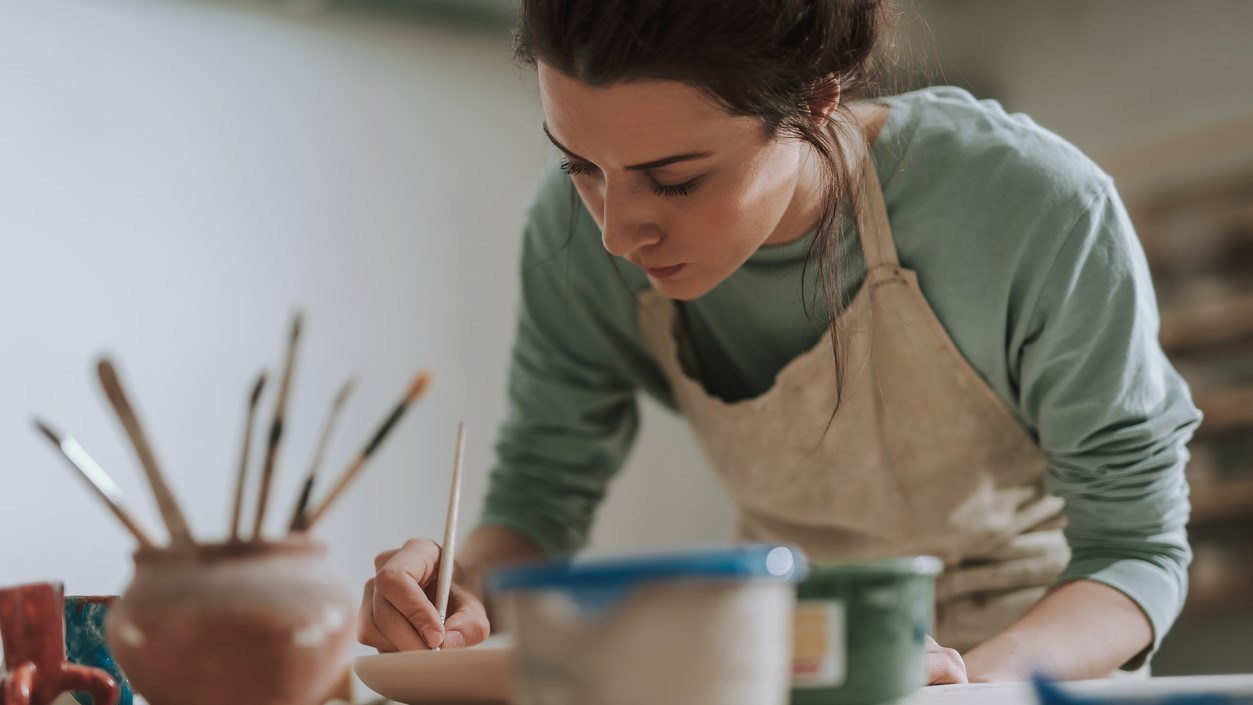 Woman painting surrounded by art supplies