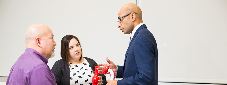 Dr. Cherrie Abraham talks with a patient about aortic surgery. He uses a model of the heart to help explain the procedure.