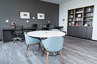 The library and business center is a shared space with table and chairs, desk space with easy outlet and internet access, and bookshelves.