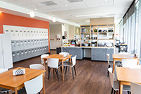 The shared dining area has tables and chairs for families, dishes and flatware, and lockers for families to store belongings.