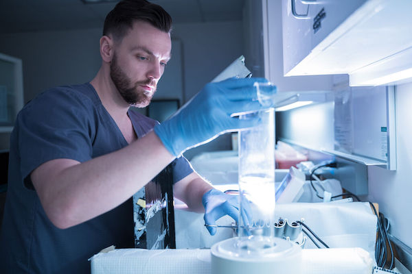 A nuclear medicine technician holds a tube in a laboratory.