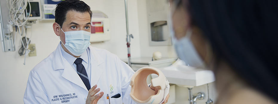 Dr. Wolfswinkel holds up a cranial orthotic helmet as he discusses its use with a patient’s parent.