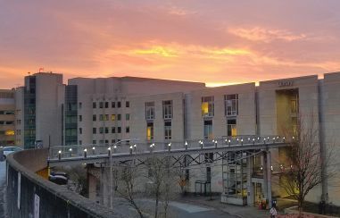 Sky bridge connecting the 博彩网站 Library to the parking ramp across the street. Hatifled Research Center building in the background with the sun setting behing the building.