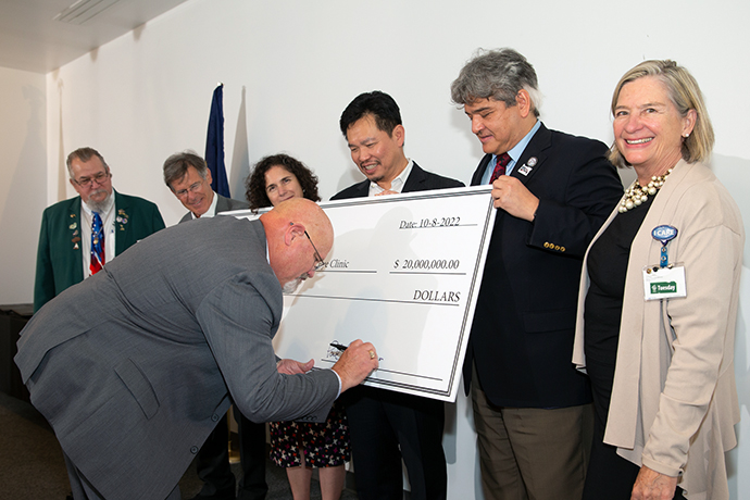 A member of the Oregon State Elks Association signs an oversized check as a symbolic donation to the Elks Children's Eye Clinic.