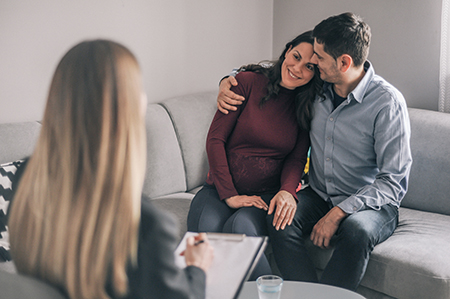A couple support each other as they meet with a genetic counselor.
