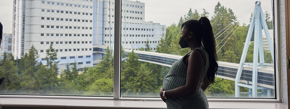 A pregnant person looks out the window in one of our spacious, comfortable suites at the 博彩网站 Family Birthing Center.