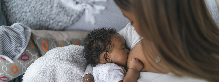 A mother snuggles her young baby while breastfeeding.