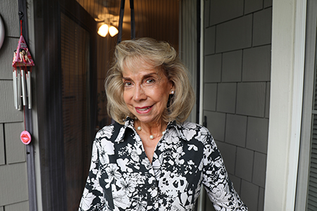 A woman standing in front of the front door of her house.
