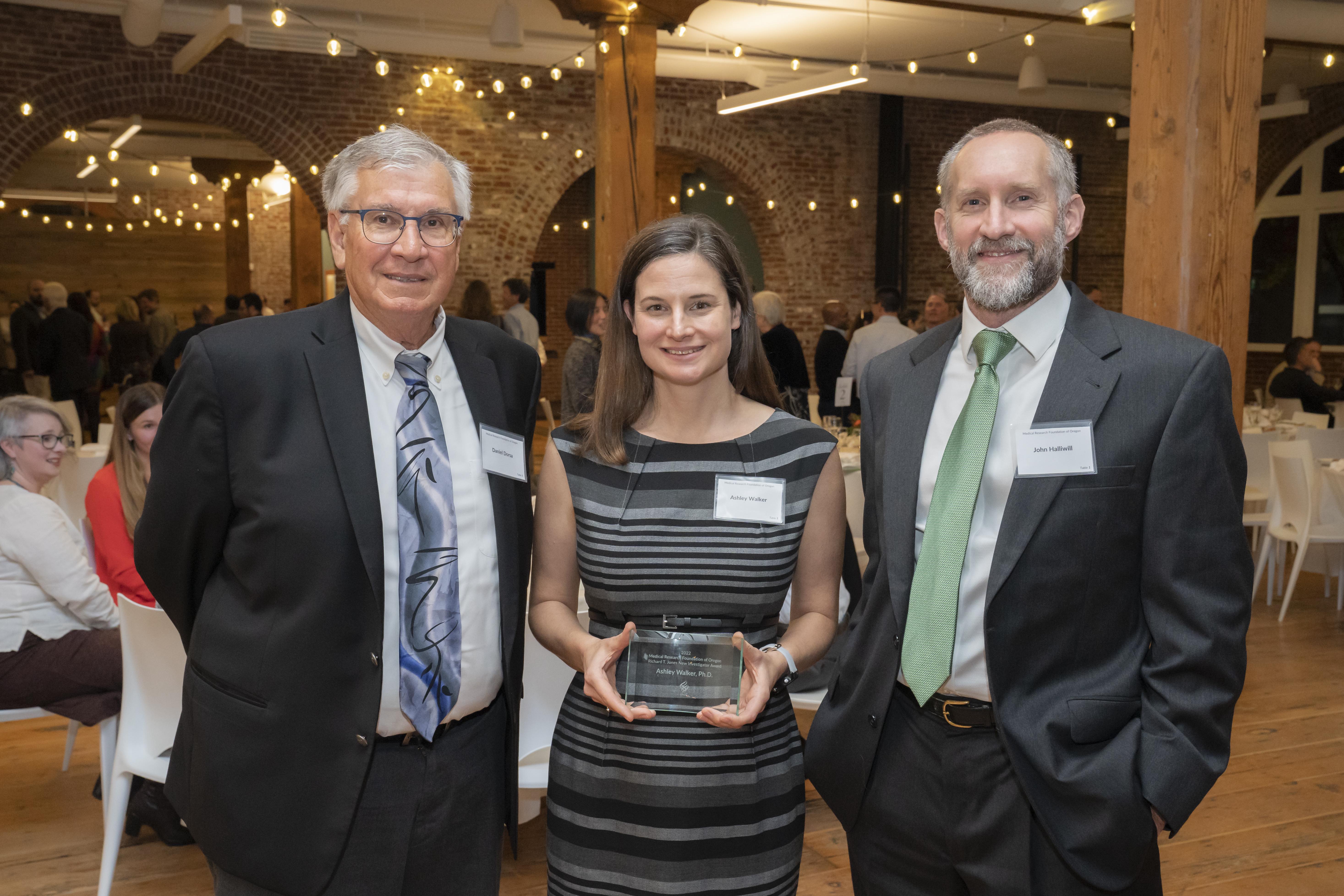A photo of Ashley Walker, Ph.D., flanked by MRF Chair Dan Dorsa, Ph.D. to the left and John Halliwell, Ph.D. to the right