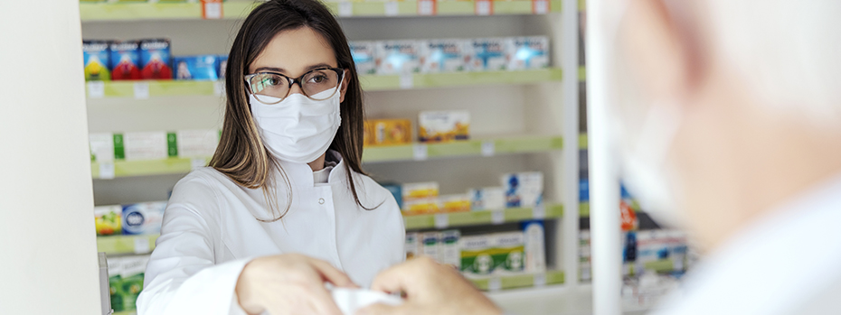 A pharmacy tech gives a bag with prescription medication inside to a customer.]