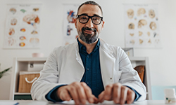 A man wearing a lab coat sitting at a desk typing on a keyboard.