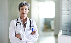 A female doctor stands with her arms crossed.