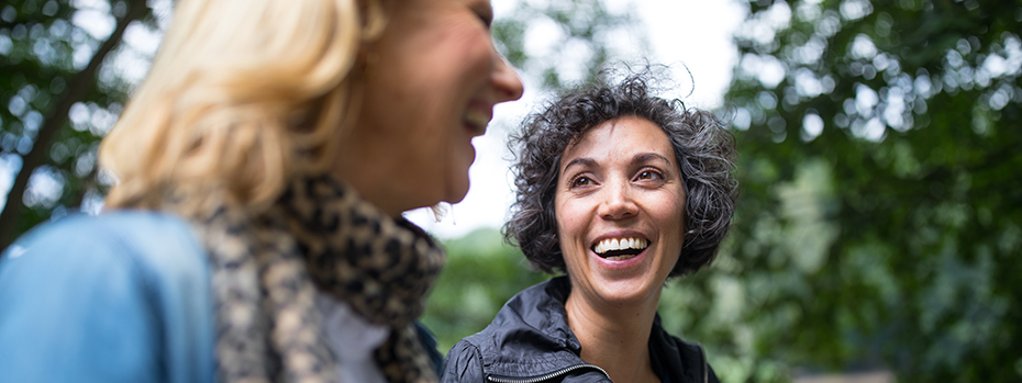 Two women walk together outside in fall weather.