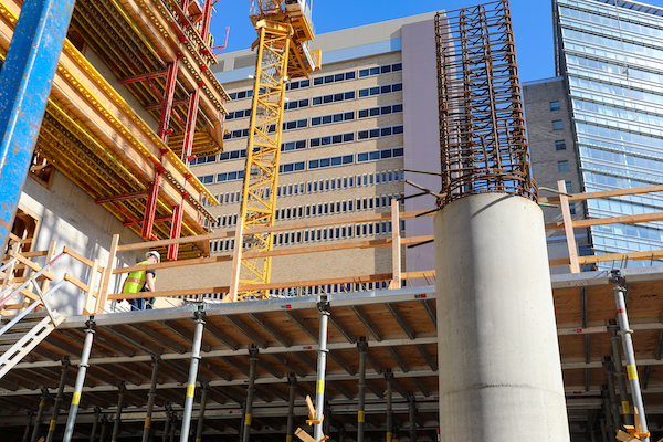 The photo, angled toward the sky, shows the partly constructed new building with 博彩网站 Hospital behind it.
