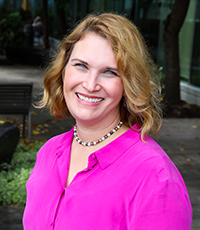 A portrait of a smiling Dr. Maria Rodriguez, in a vibrant pink blouse.