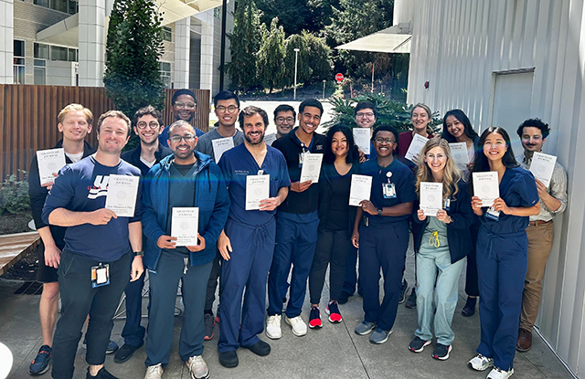 A group stands together posing for the camera, each holding a white brochure on wellness.