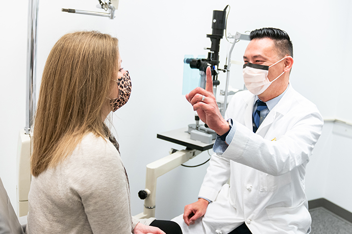 Dr. Derek Louis holds up a finger as part of an eye exam for a patient.