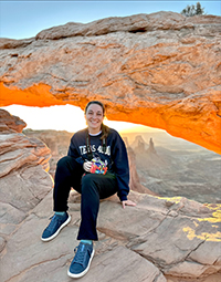 A woman sitting in front of the Mesa Arch in Canyonlands National Park.