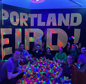 A group sits in a ball pit in front of a large "Keep Portland Weird" sign.