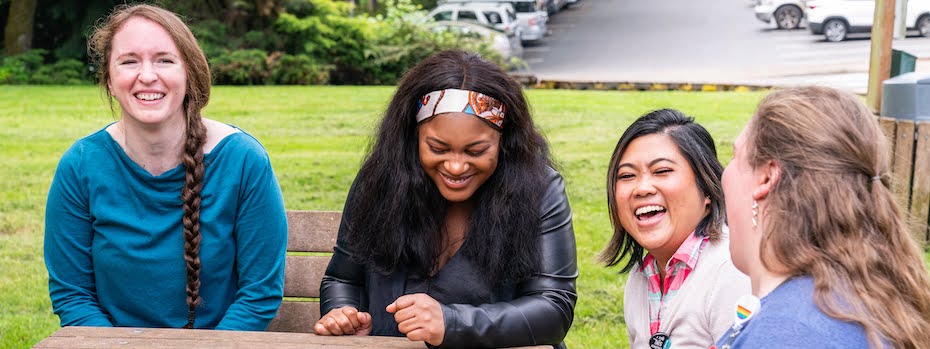 Four nursing students laughing as they chat together outside the School of Nursing building.