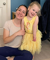 A woman sitting on the floor next to a standing little girl.