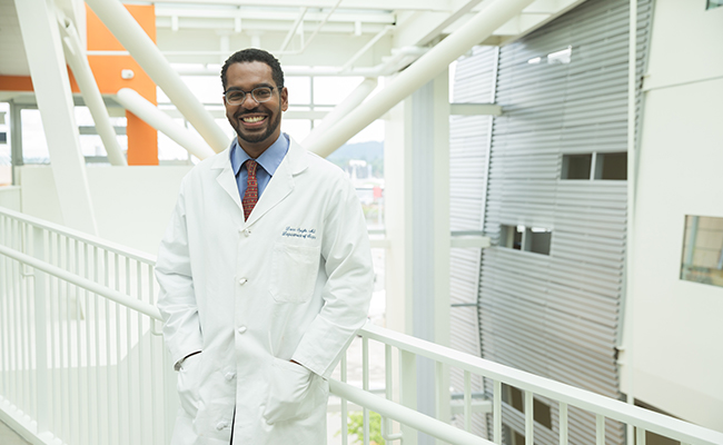 Dr. Donn Spight standing, hands in the pockets of his medical white coat, smiling while standing in an 博彩网站 clinical building.