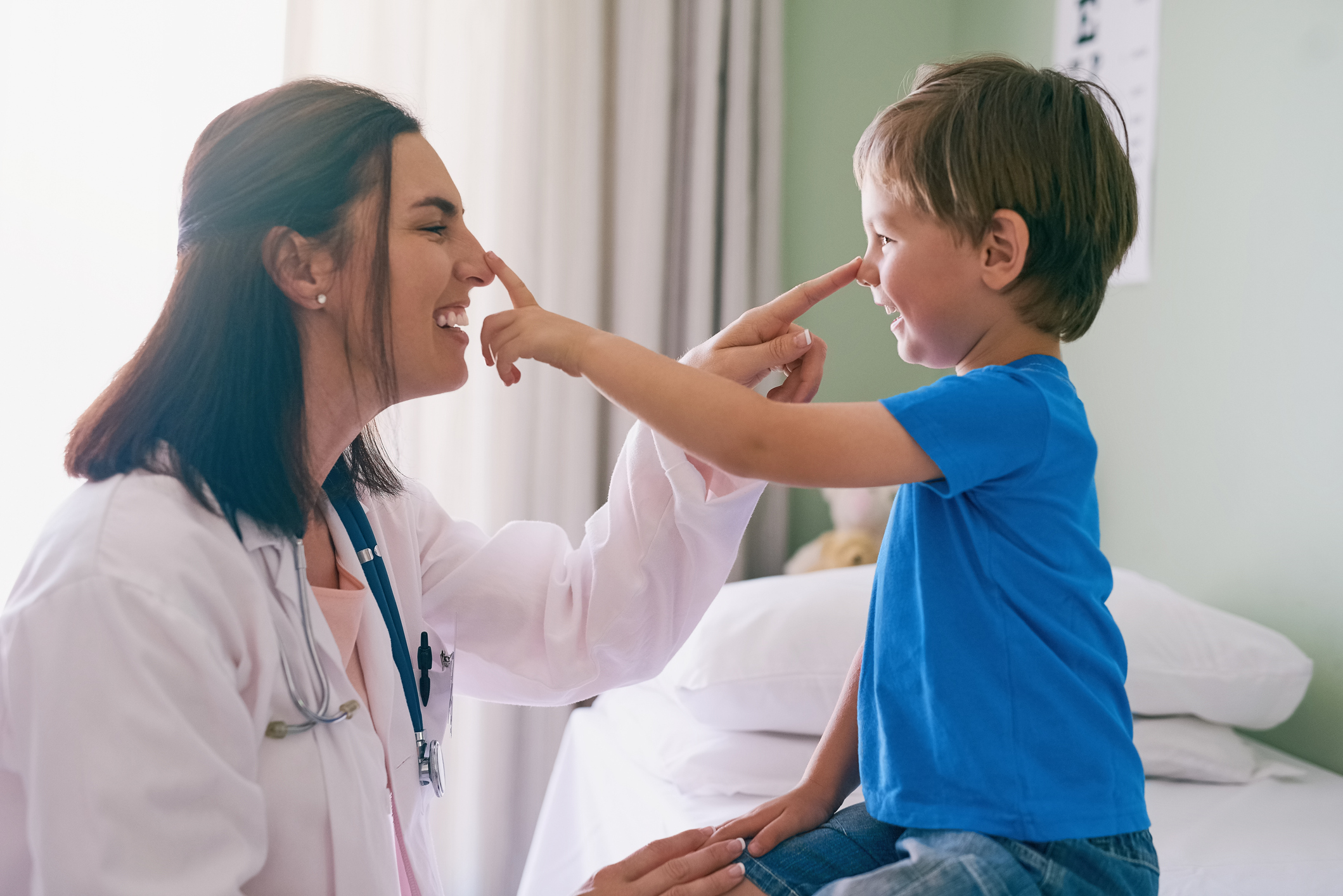 A young female doctor and her young male patient touch each other's noses.