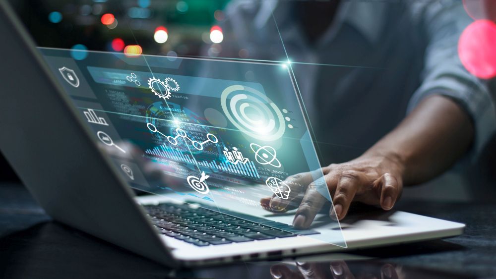 A data dashboard visualized above a laptop with a hand on the laptop.