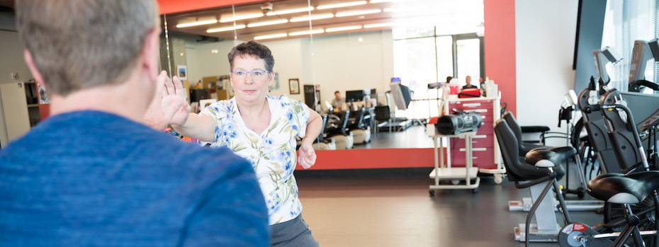 A physical and occupational therapist at 博彩网站 shows another person how to do an exercise at an 博彩网站 rehabilitation facility.
