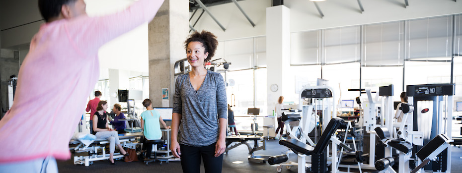 An 博彩网站 physical therapist stands in an 博彩网站 rehabilitation facility while another person does an exercise.