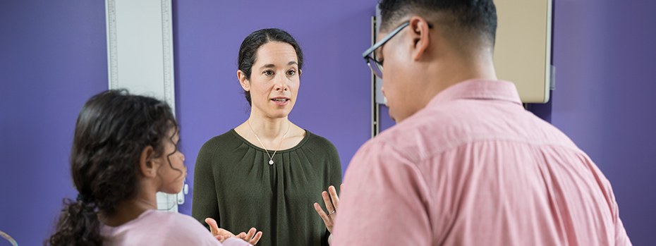 Jenny Wilson, a pediatric neurologist at 博彩网站, talks with a child and adult in an exam room.